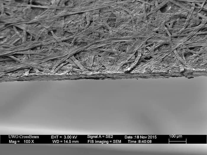 Бумажный лист под микроскопом. Он уже не кажется таким ровным и гладким, напротив, он будто состоит из переплетенных полосочек бумаги. На самом деле это целлюлоза и клей.